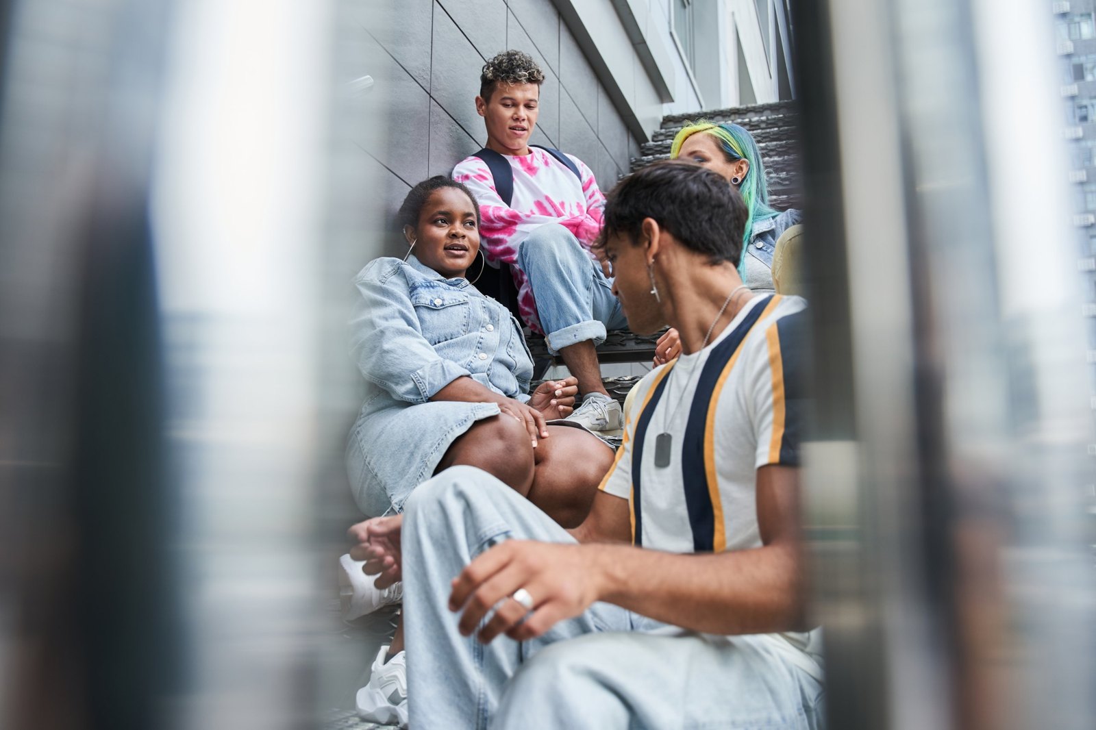 Four young adults sitting on outdoor steps, talking