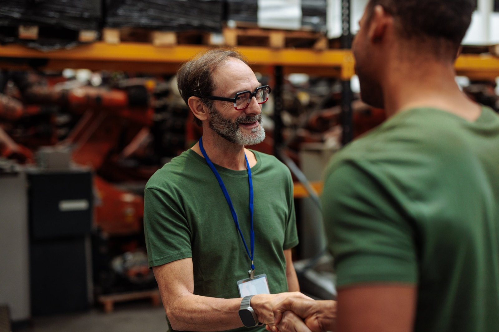 A supervisor shaking hands with a new coworker on a warehouse floor